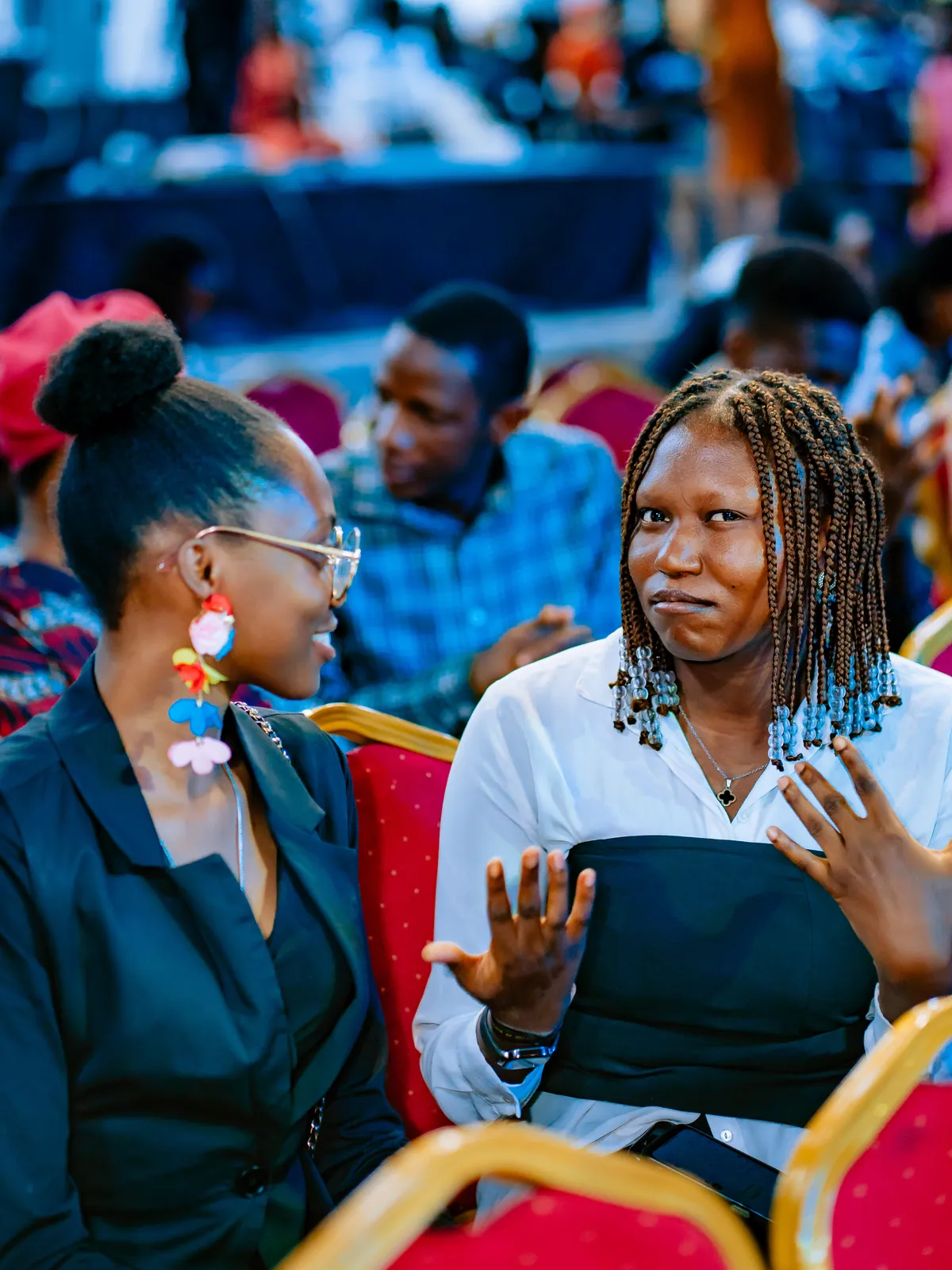 Two women in conversation in the audience at CTC 2.0, one gesturing as she talks.