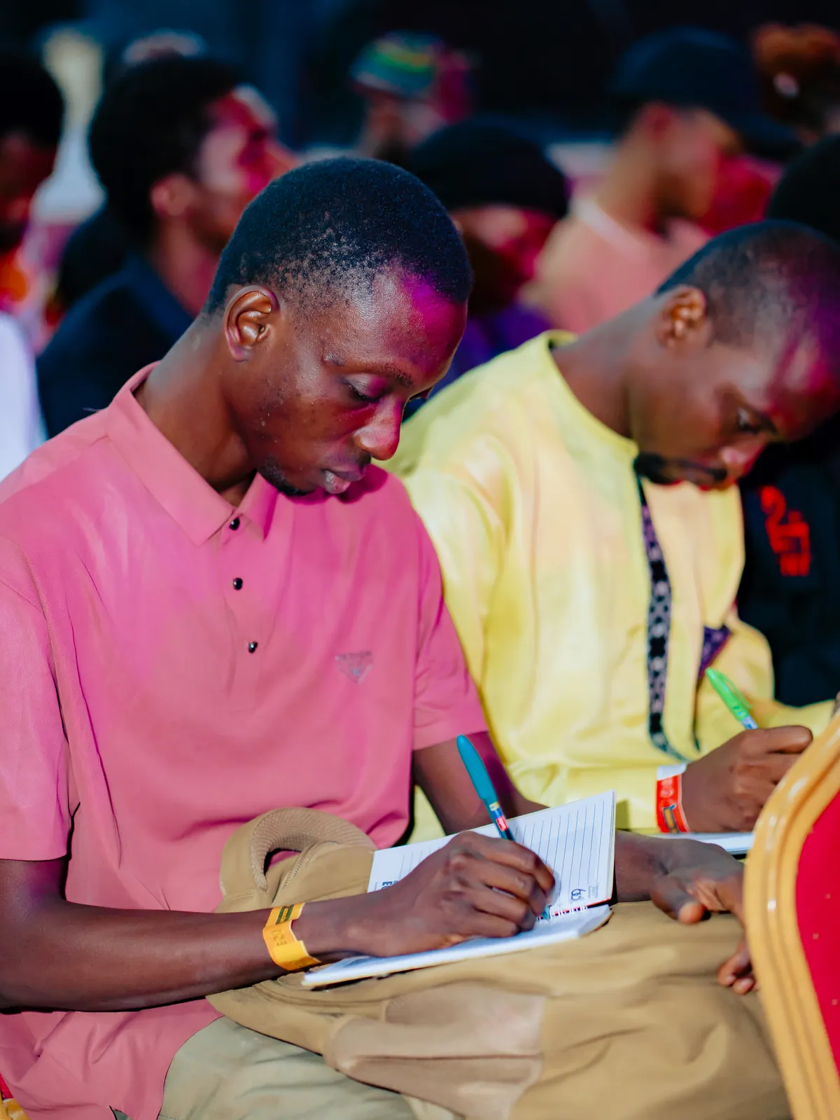 Two attendees seated side by side writing in notebooks at CTC 2.0.